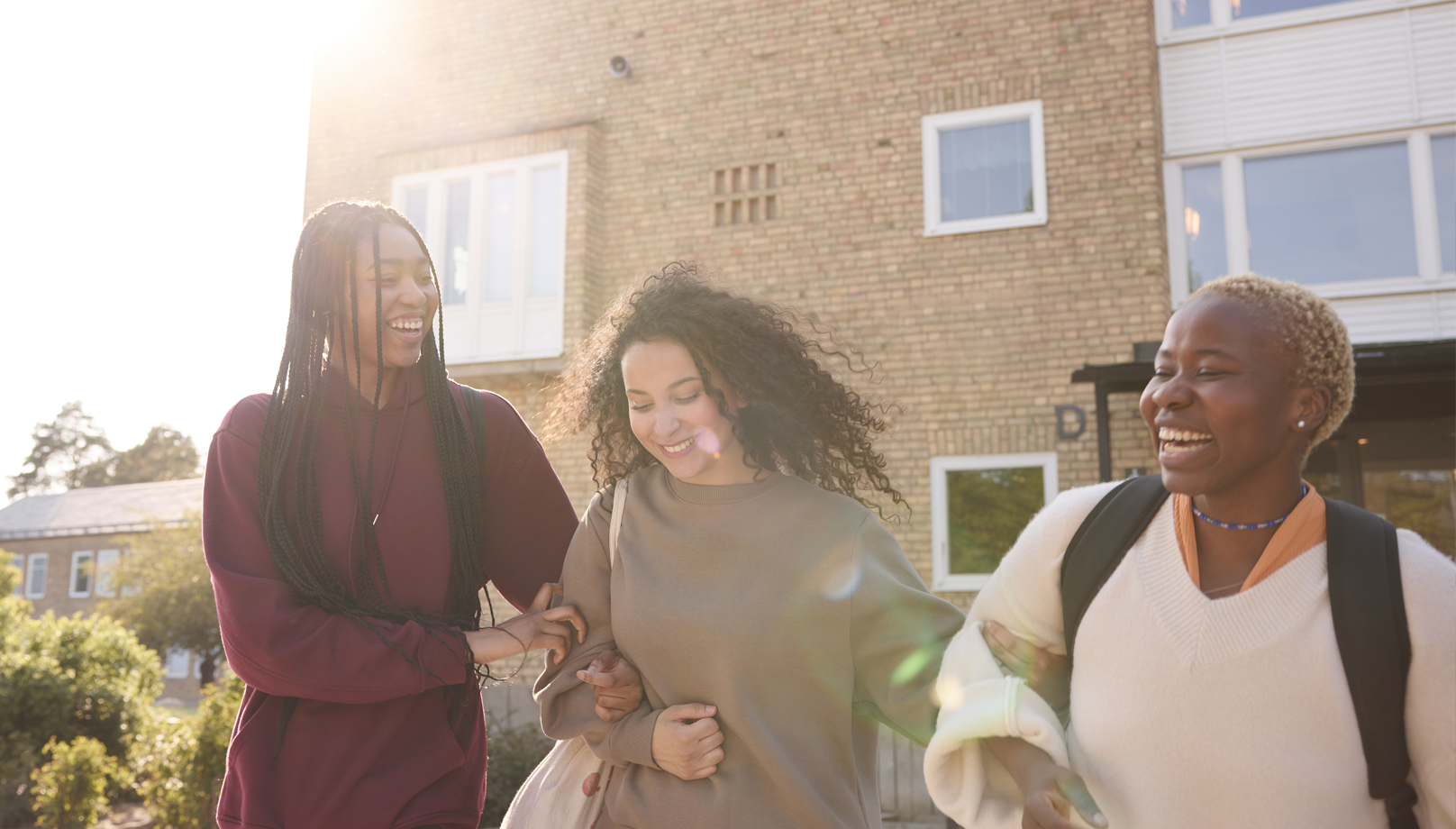 Tre skolungdomar utanför en skola.