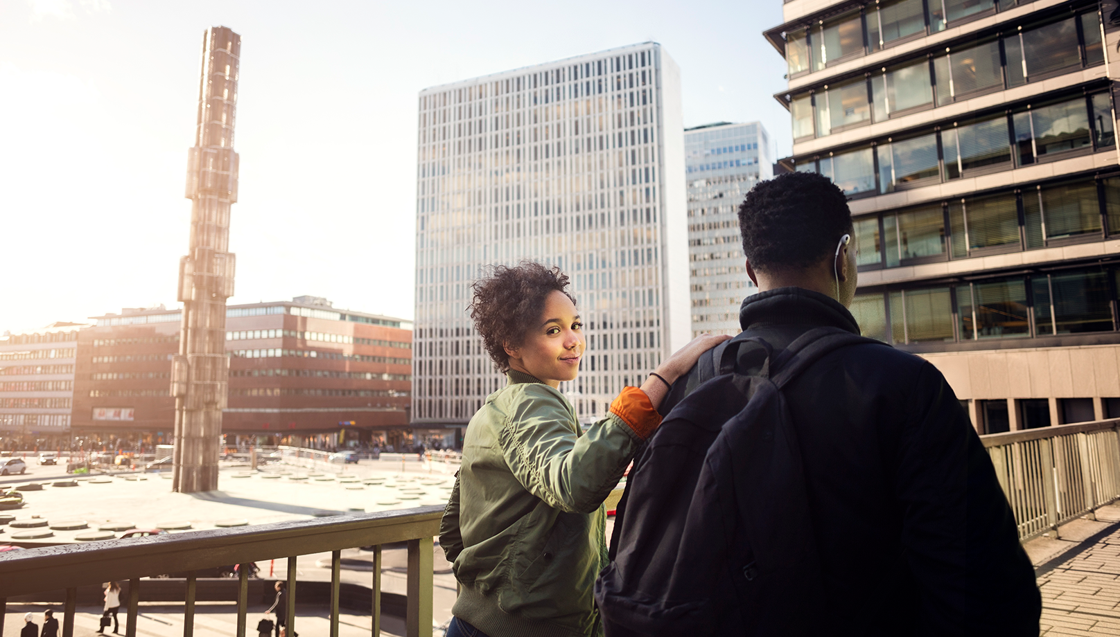 En kvinna och en man går tillsammans på en bro i en stadsmiljö